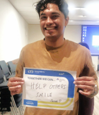 Samuel Pugo holding his sign to "Help Others Smile" 